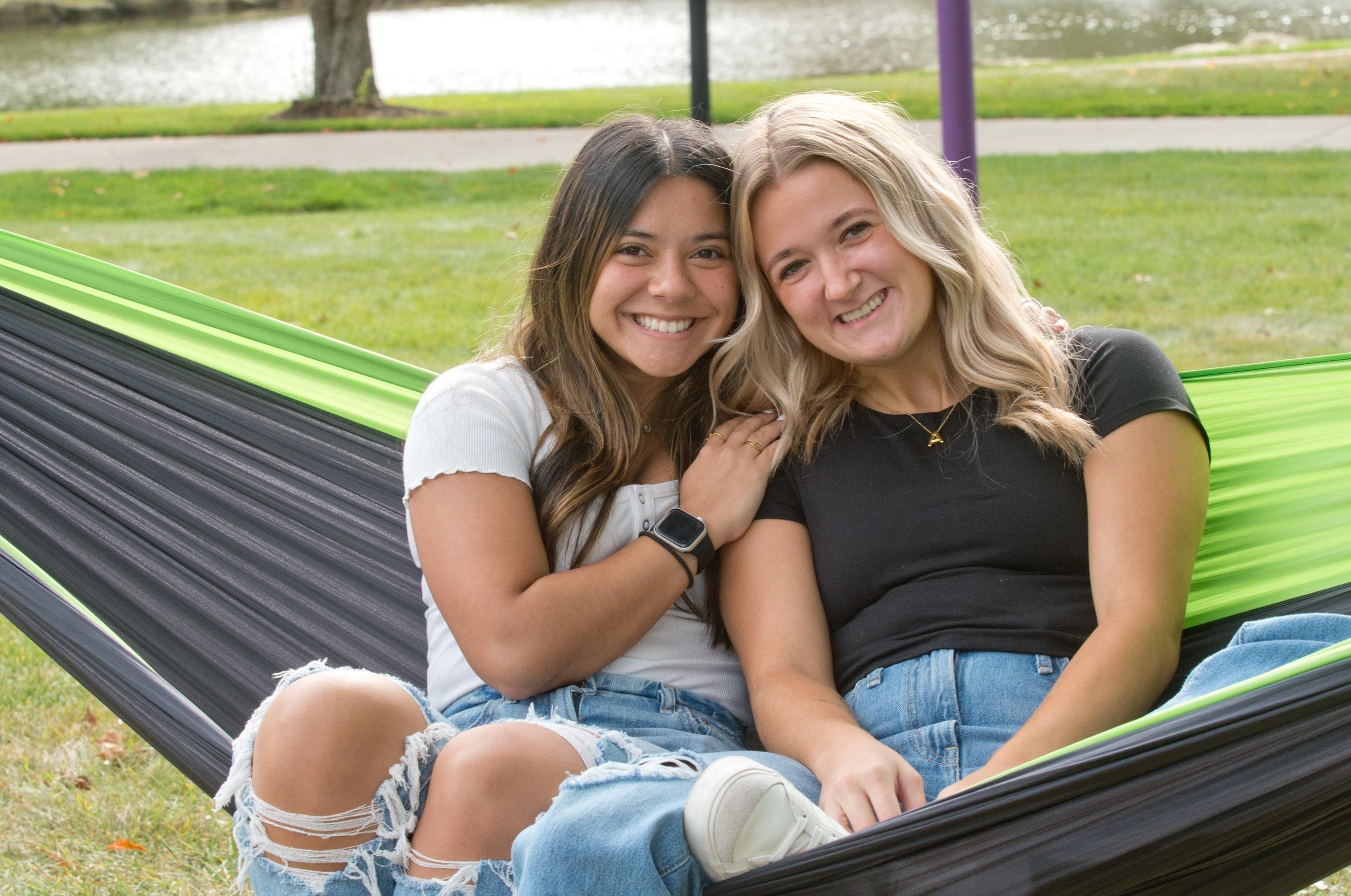 Mount Union students smiling on a hammock by 的 lakes.